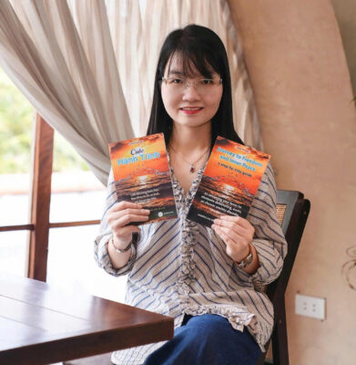 Author Doan Thi Lam holding both the Vietnamese and English editions of the book Journey to Freedom and Inner Peace.